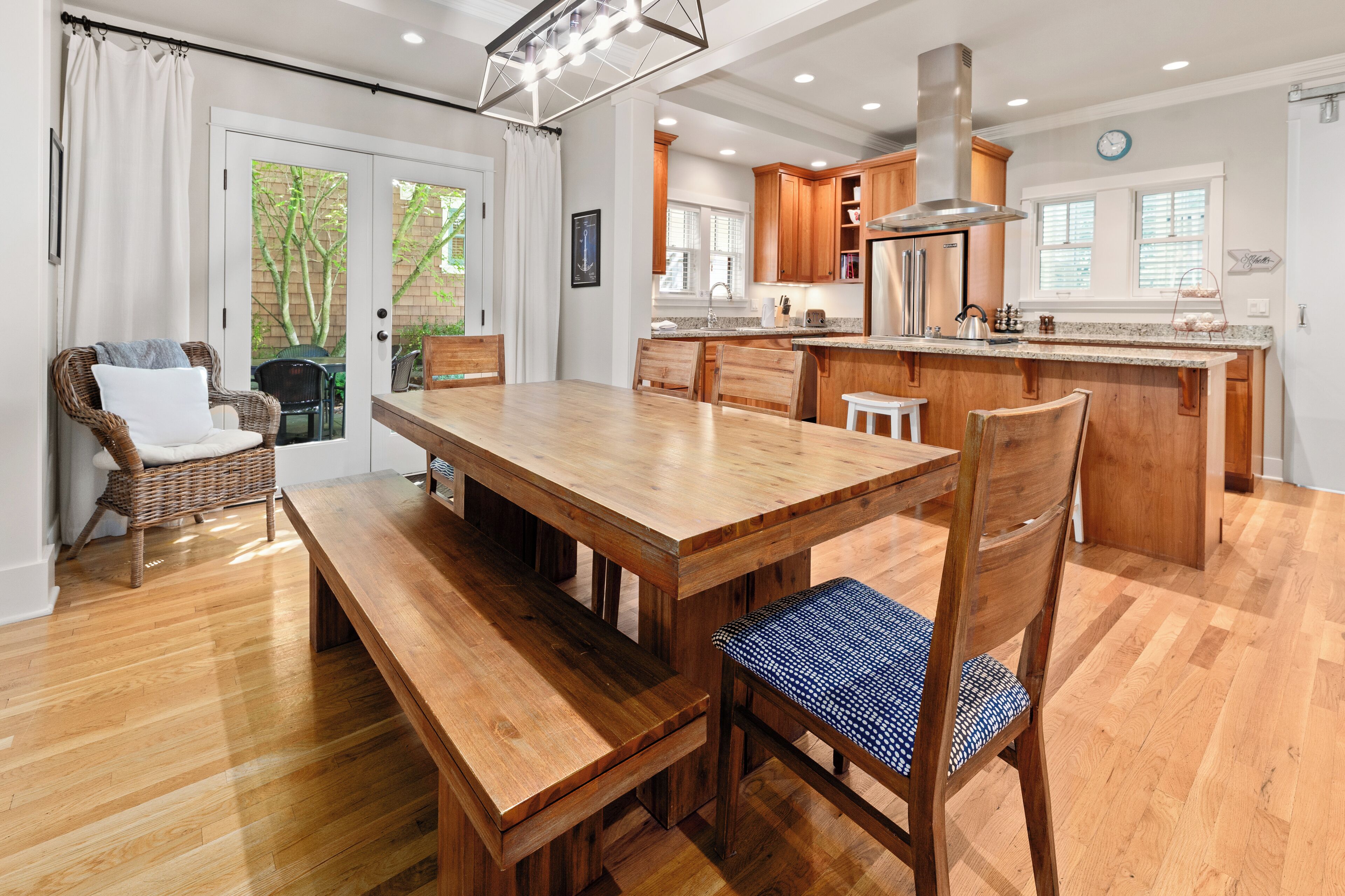Una cocina amplia con armarios de madera, una isla central y un comedor con banco y sillas.