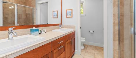 A modern bathroom with two sinks, a large mirror, and a glass shower enclosure.