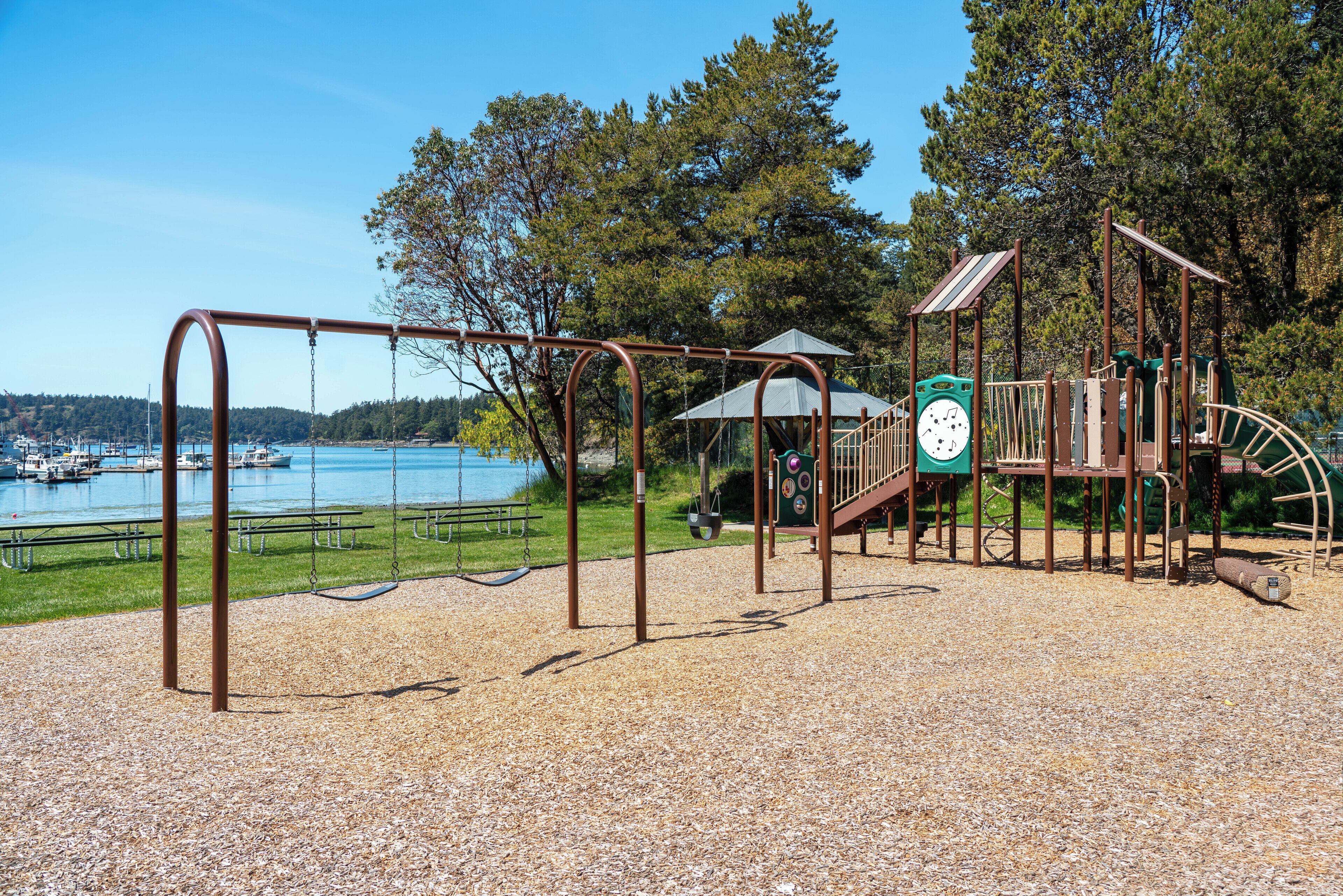 A playground with swings and a climbing structure near a lake.
