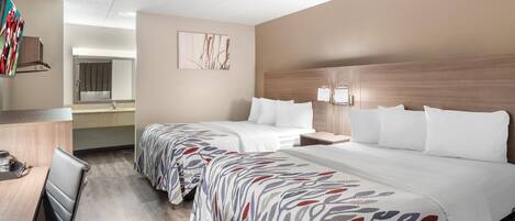Een hotelkamer met twee bedden, een bureau, een stoel, een spiegel en een kunstwerk aan de muur.