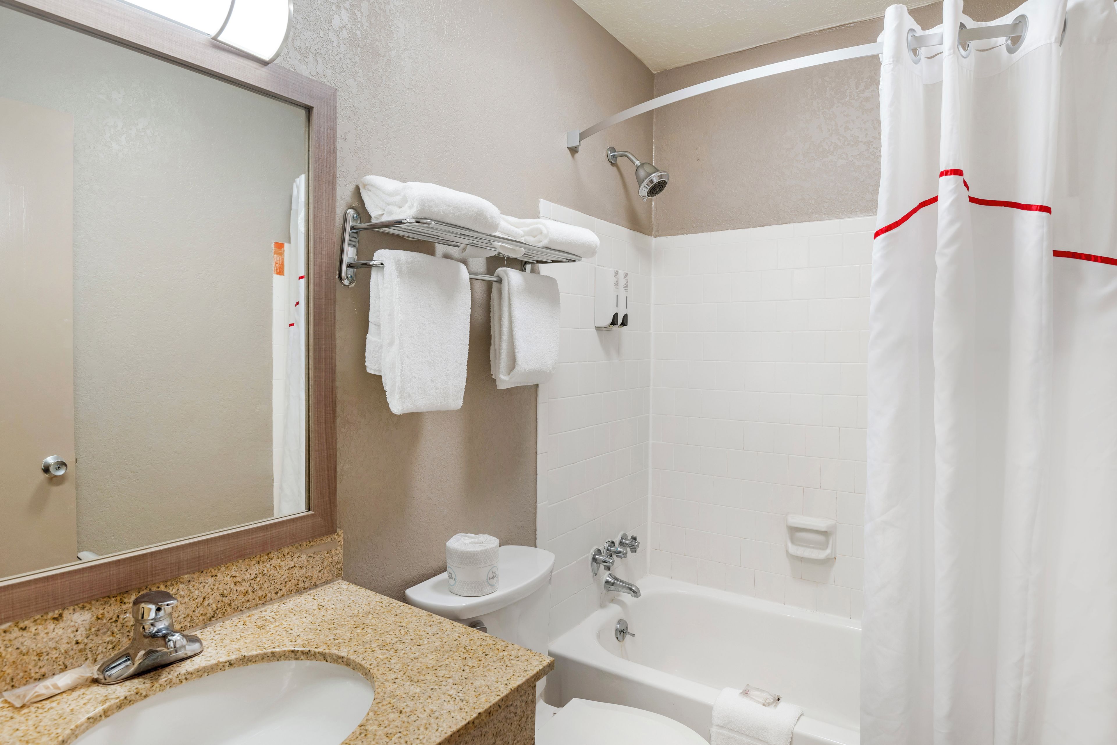 A bathroom with a sink, toilet, bathtub, and shower curtain.