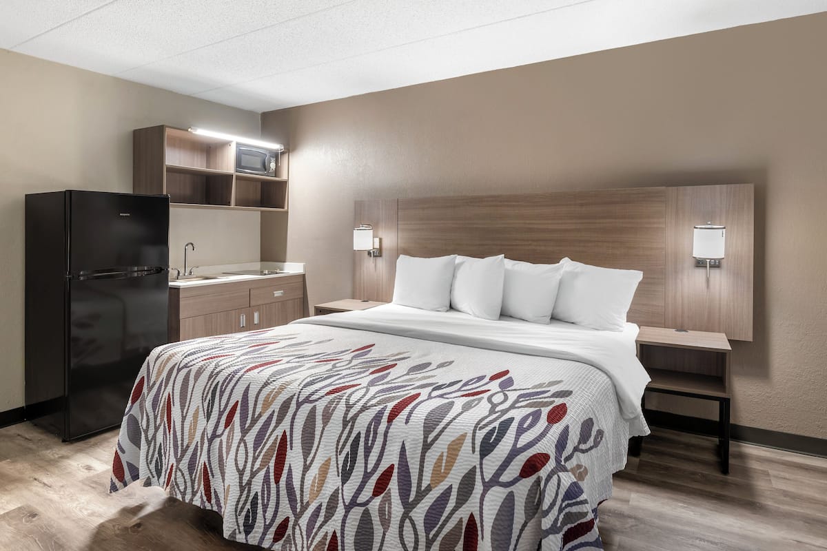 Een hotelkamer met een bed, een koelkast, een magnetron, een wastafel en een kast.