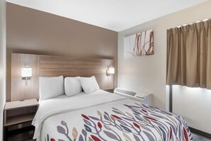 Habitación de hotel con cama, mesitas de noche, aire acondicionado de pared y ventana con cortinas.