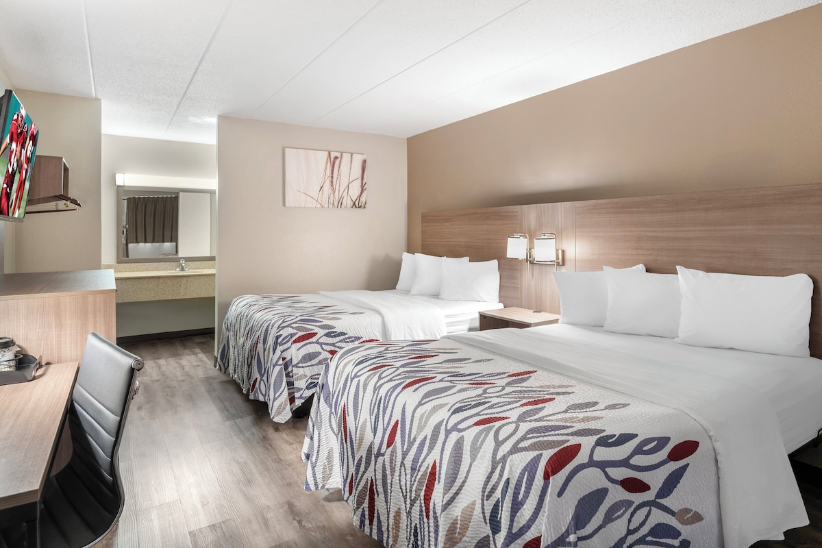 Une chambre d’hôtel avec deux lits, un bureau et une chaise.