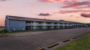 Un motel avec un toit plat, plusieurs chambres et un parking.