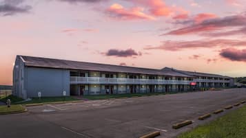 Un motel con techo plano, varias habitaciones y un estacionamiento.