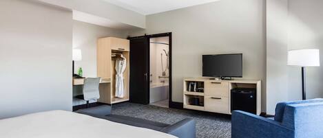 A hotel room with a bed, a desk, a TV, a wardrobe, and a bathroom.