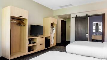 A hotel room with a bed, a TV, a wardrobe, and a bathroom with a mirror.