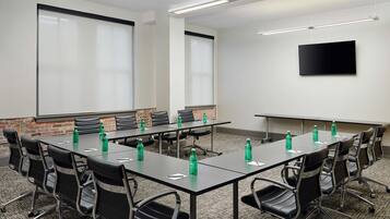 A conference room with a long table, black chairs, and green water bottles.