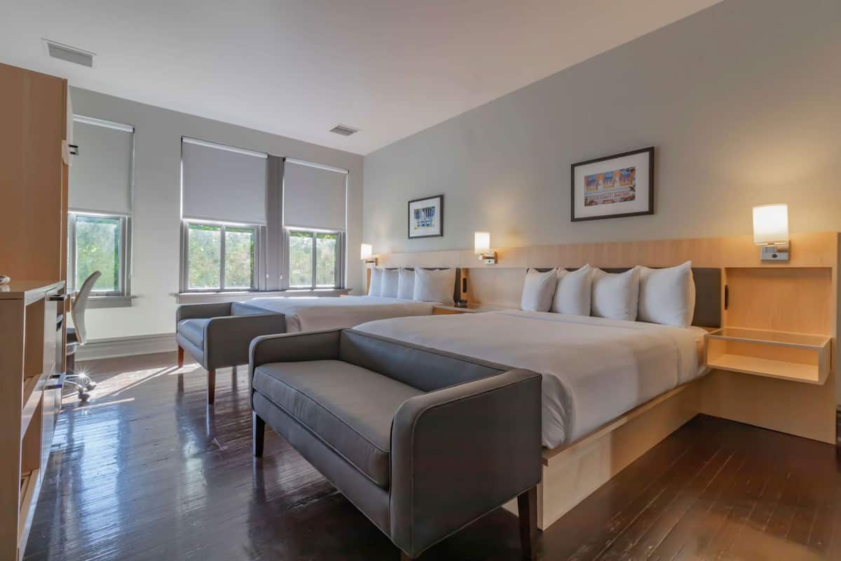 A hotel room with a large bed, a desk, a chair, and a window.