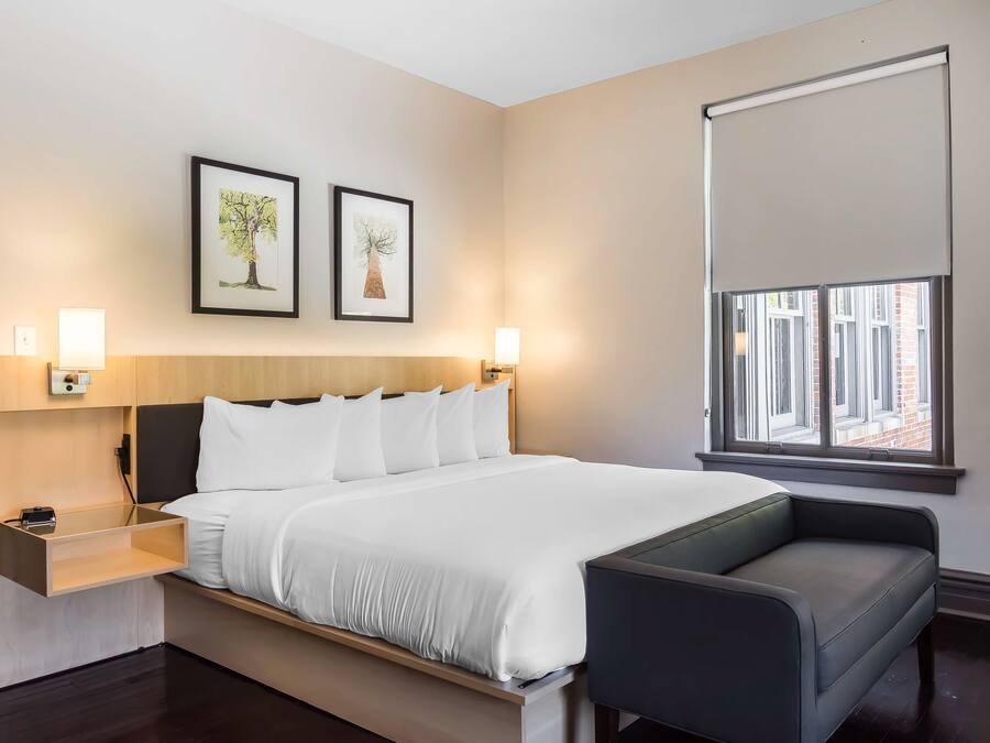 Een moderne hotelkamer met een groot bed, nachtkastjes, een bureau en een raam met jaloezieën.