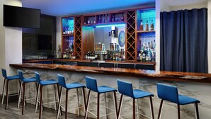 A bar area with a counter, bar stools, and shelves stocked with bottles and glasses. - The Waters Hot Springs, Tapestry Collection by Hilton (Hot Springs)
