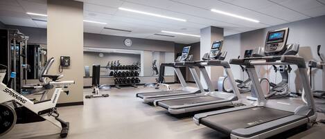 A gym with multiple treadmills, weight machines, and dumbbells.