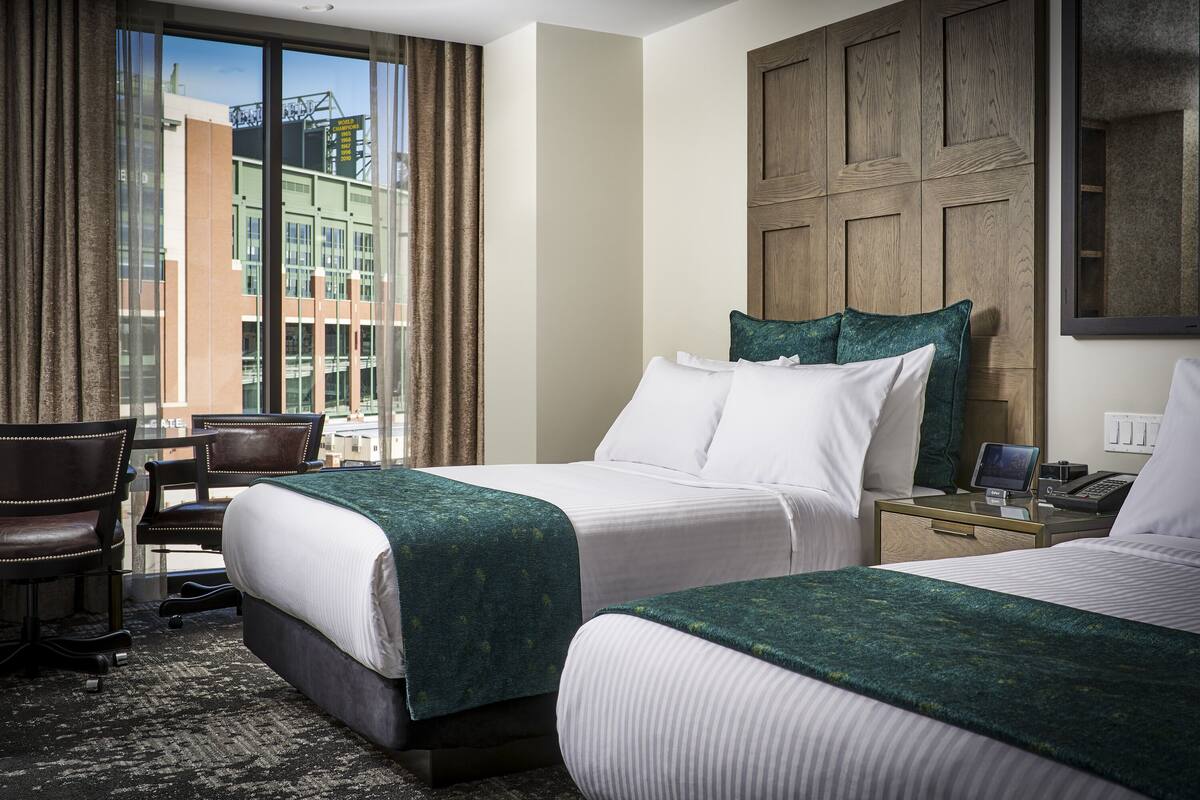Habitación de hotel con dos camas, un escritorio y una silla.