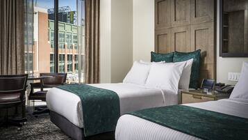 A hotel room with two beds, a desk, and a chair.