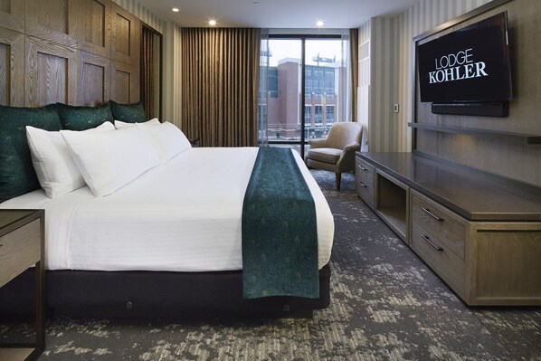 A hotel room with a large bed, a television, a chair, and a view of the city through the window.