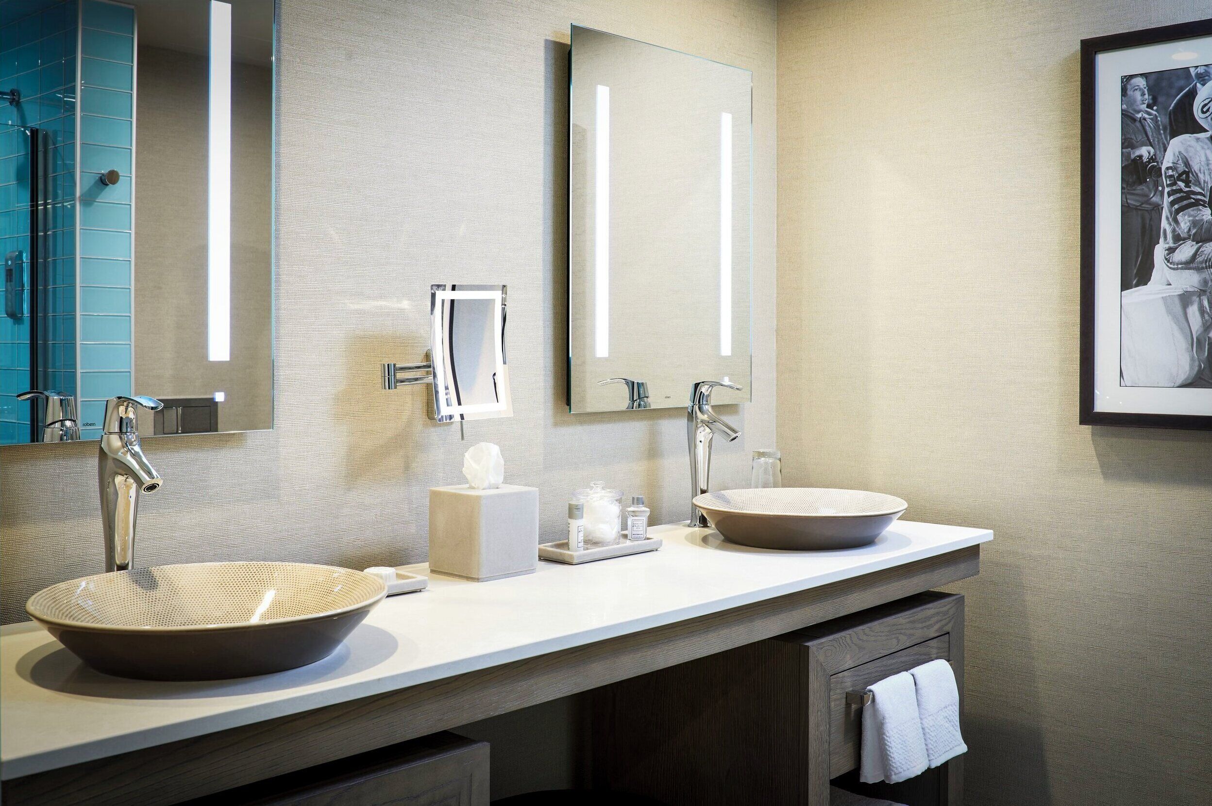 A modern bathroom with two sinks, a large mirror, and a towel rack.