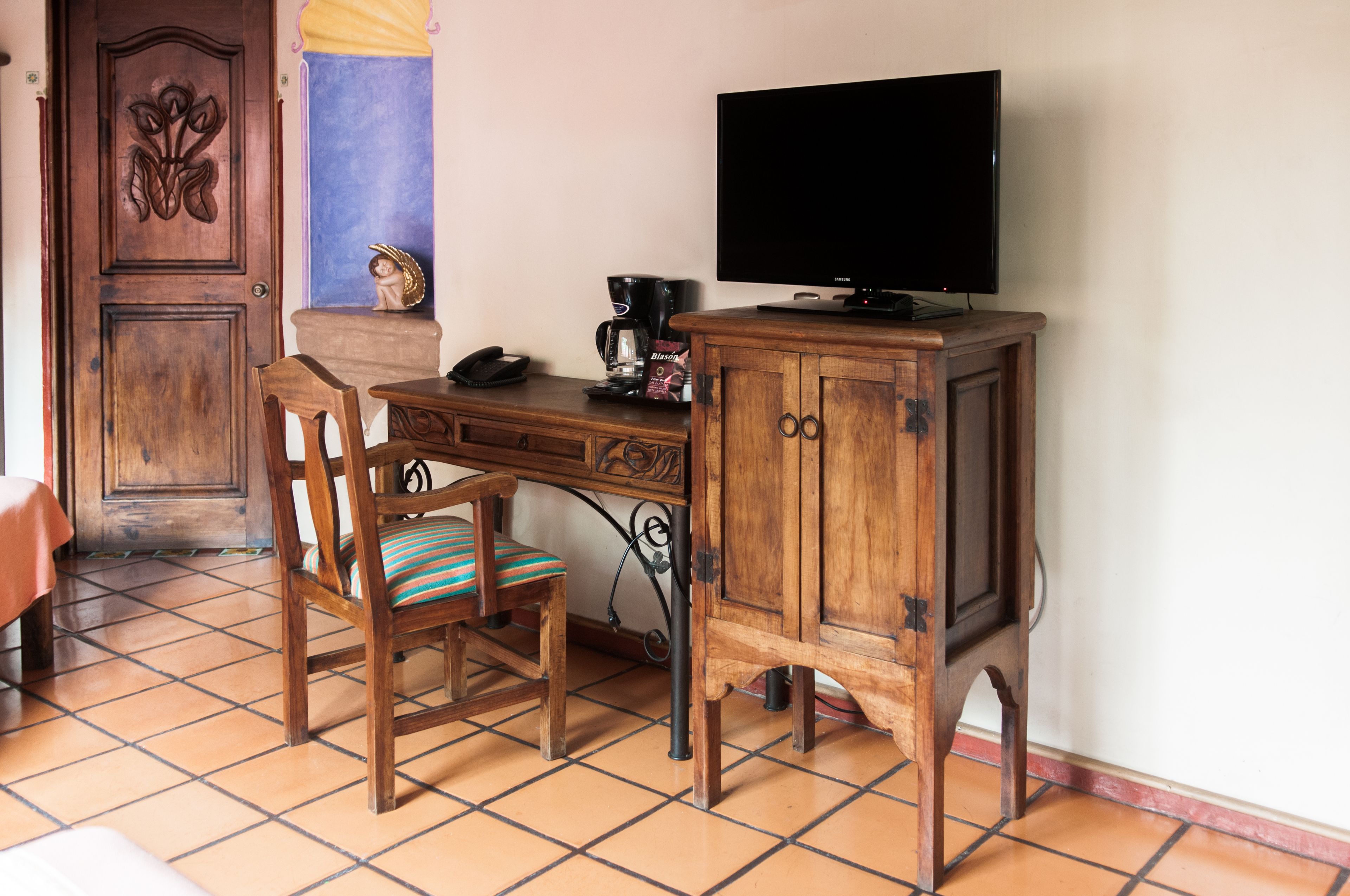 A wooden desk with a television, a chair, and a telephone.