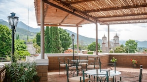 An outdoor patio with tables and chairs, a lamp, and potted plants. - Raintree`s Las Cupulas Oaxaca (San Felipe del Agua)