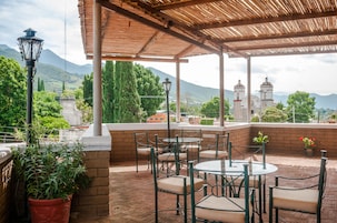 Un patio al aire libre con mesas y sillas, una lámpara y plantas en macetas.
