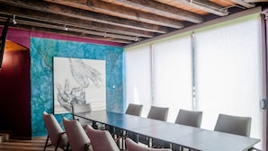 A conference room with a long table, six chairs, and a large abstract painting on the wall. - Raintree`s Las Cupulas Oaxaca (San Felipe del Agua)