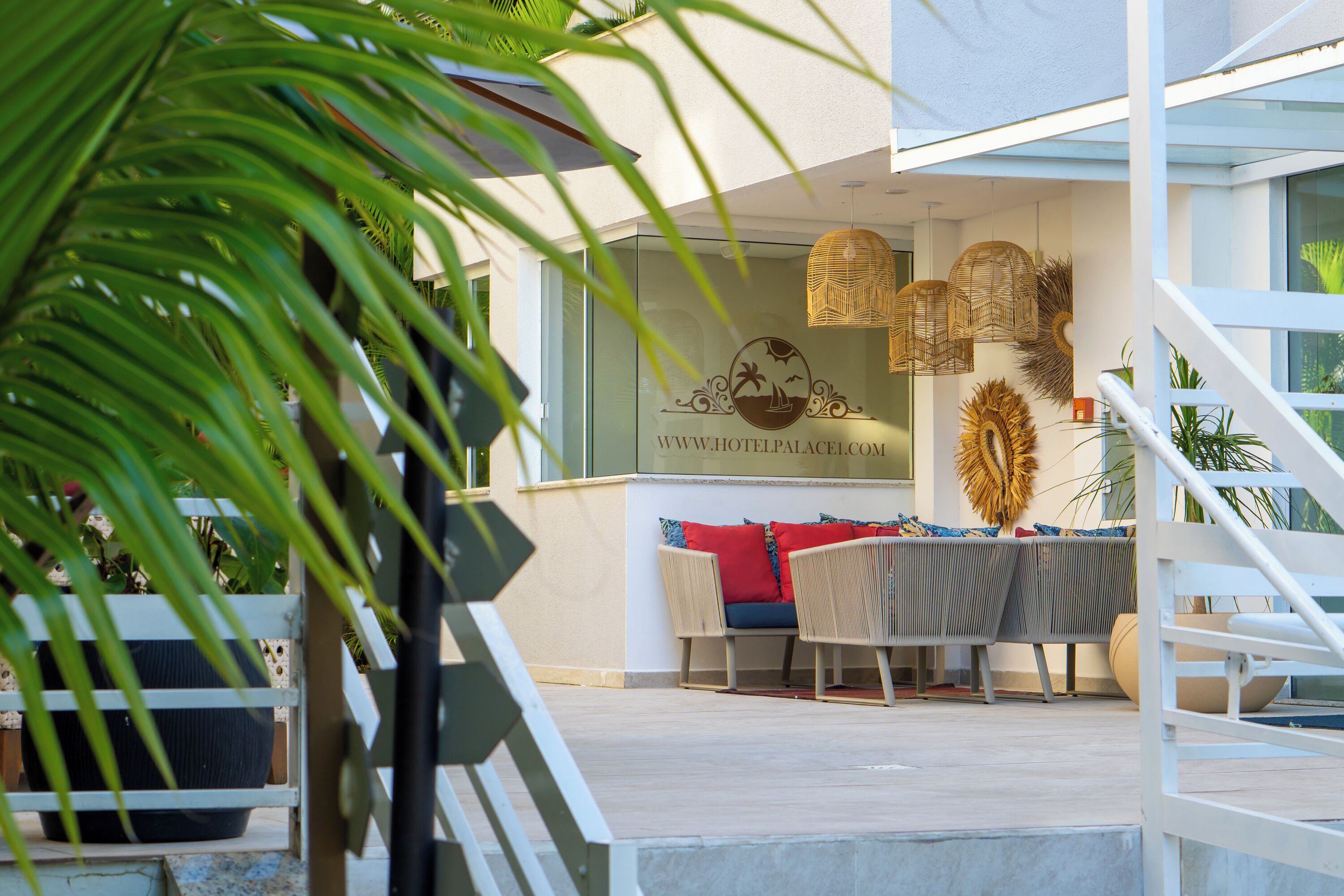 Een modern hotel met een glazen gevel, een terras en decoratieve rieten lampen.