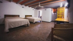 A room with two beds, a wooden ceiling, a table, and a chair.