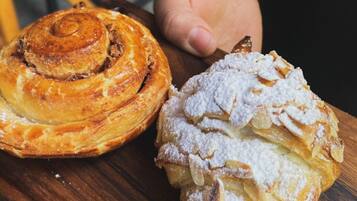 Een houten serveerplank met twee gebakjes, waarvan er één een spiraalvormig ontwerp heeft en de ander bestrooid is met poedersuiker.