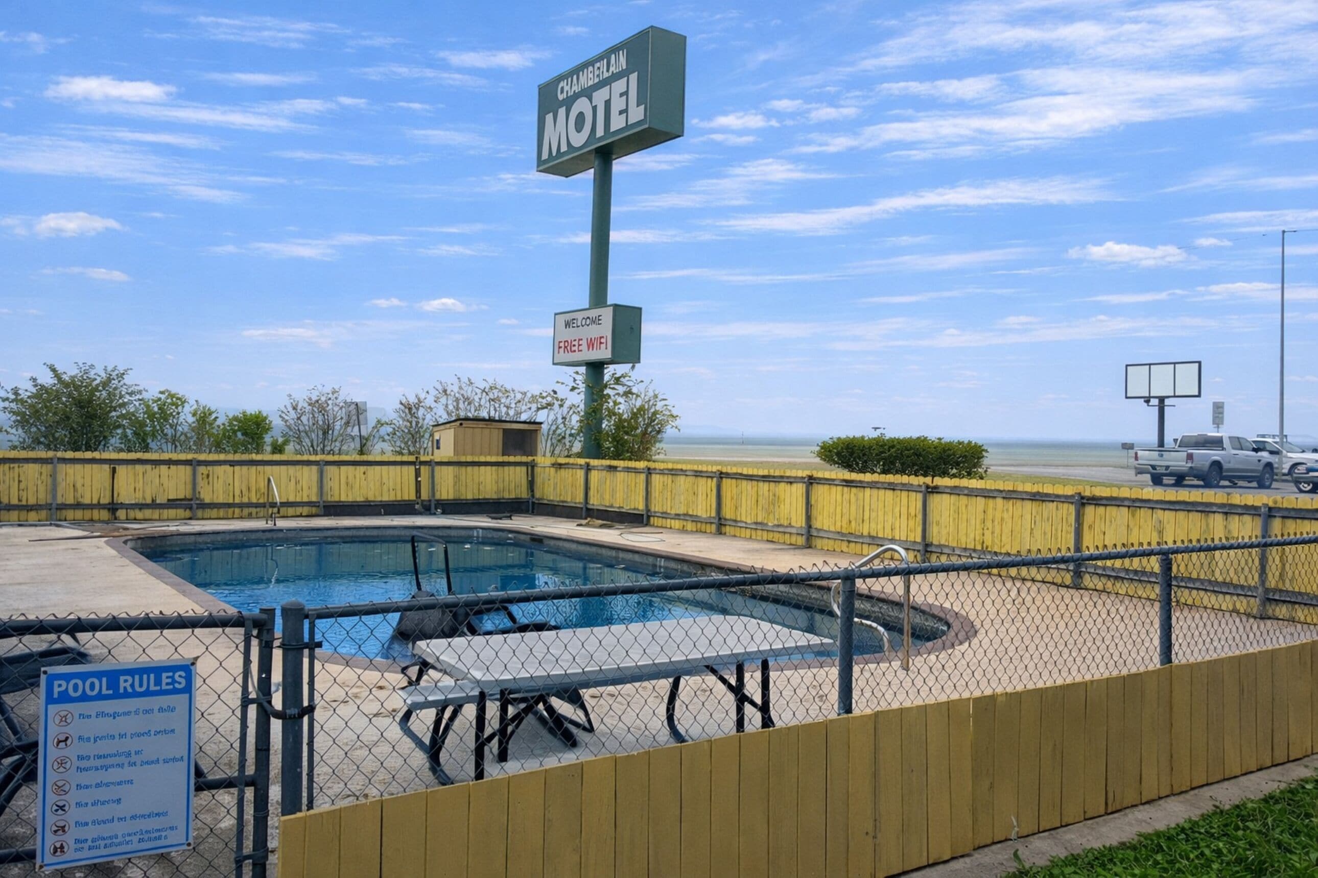 Um motel com área de piscina, incluindo uma placa com Wi-Fi gratuito e regras da piscina.