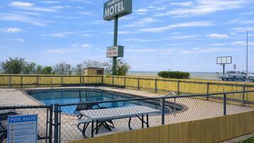 Um motel com área de piscina, incluindo uma placa com Wi-Fi gratuito e regras da piscina.