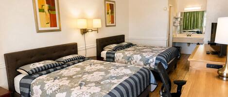 Habitación de hotel con dos camas, un escritorio, una silla, un espejo y lámparas de pared.