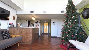 A hotel lobby with a reception desk, a Christmas tree, a sofa, and a chair. - Chaparral Motel Victoria TX US 59 (Victoria)