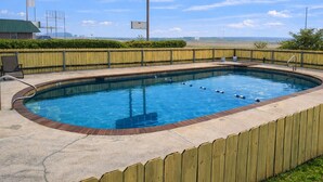A rectangular swimming pool with a wooden fence, a concrete deck, and a metal ladder. - Chaparral Motel Victoria TX US 59 (Victoria)
