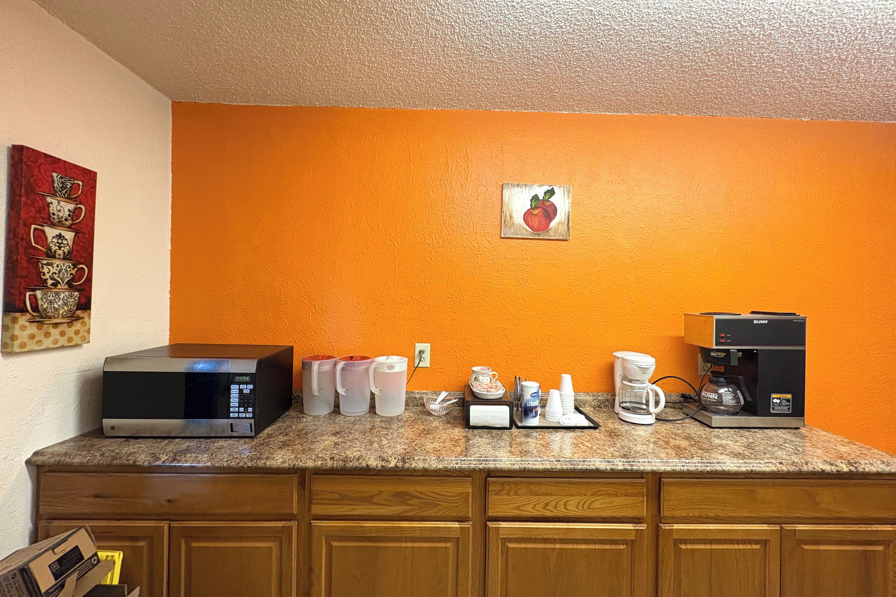 A kitchen with a microwave, coffee maker, and various kitchenware on the counter.