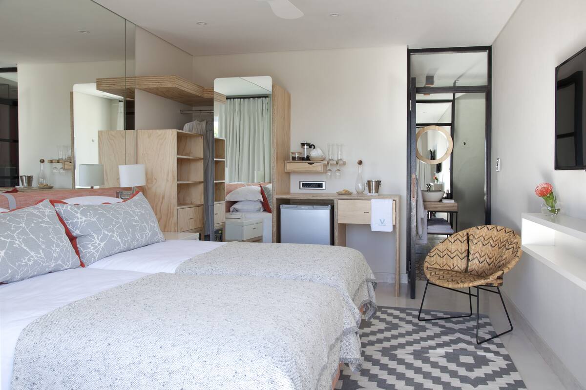 Una habitación de hotel moderna con una cama grande, un escritorio, una silla y una pequeña kitchenette.