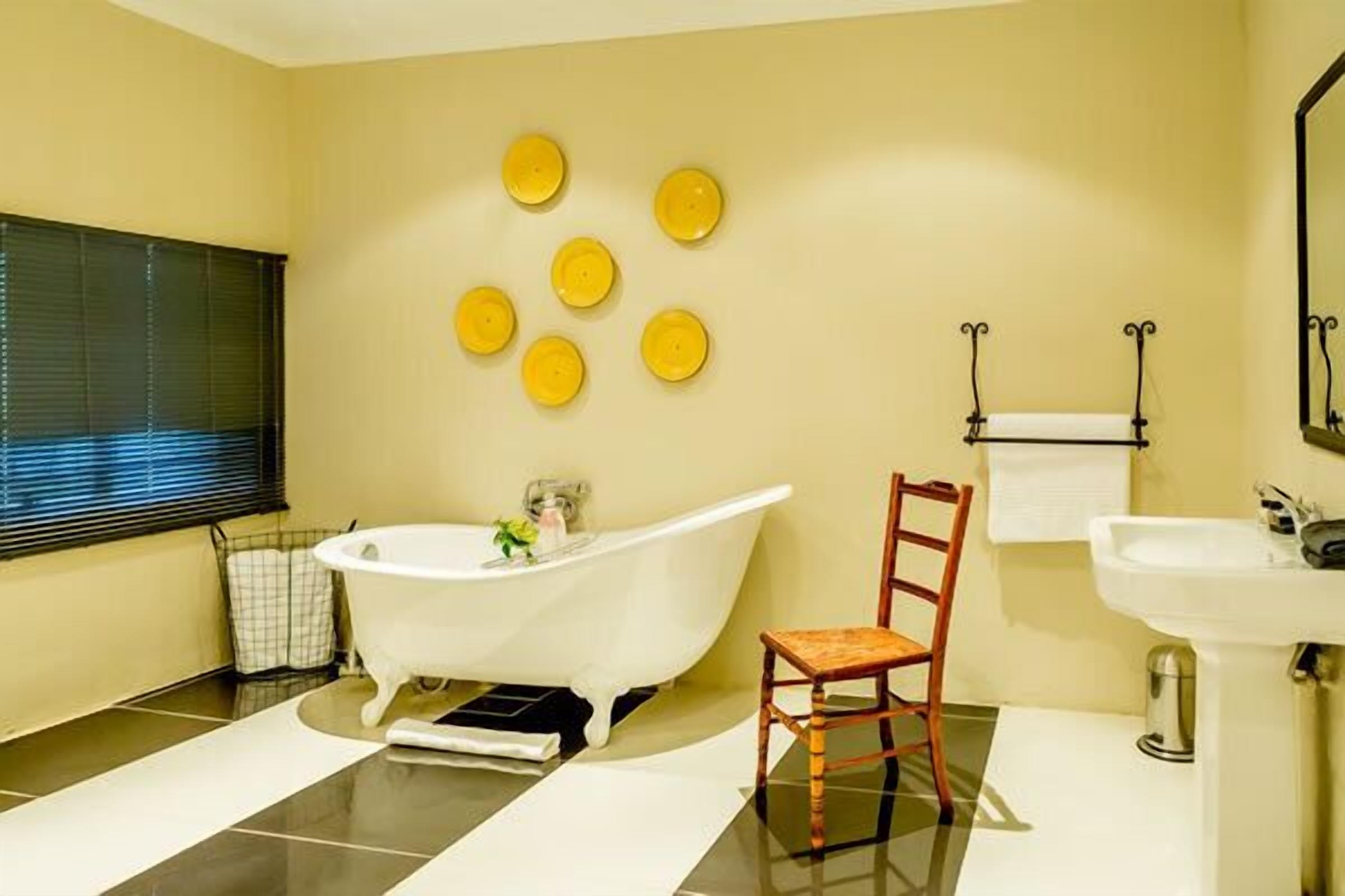 A bathroom with a freestanding bathtub, a wooden chair, a sink, and a mirror.