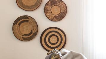 A room with a woven chair and a wall adorned with four circular woven wall hangings.