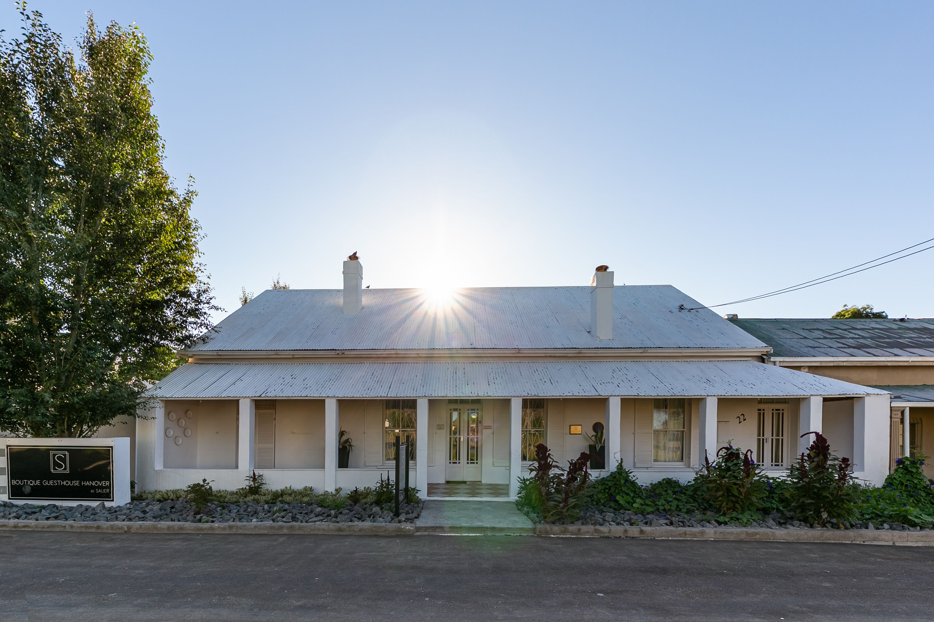 A two-story building with a flat roof, a front porch, and a sign indicating it is a guesthouse.