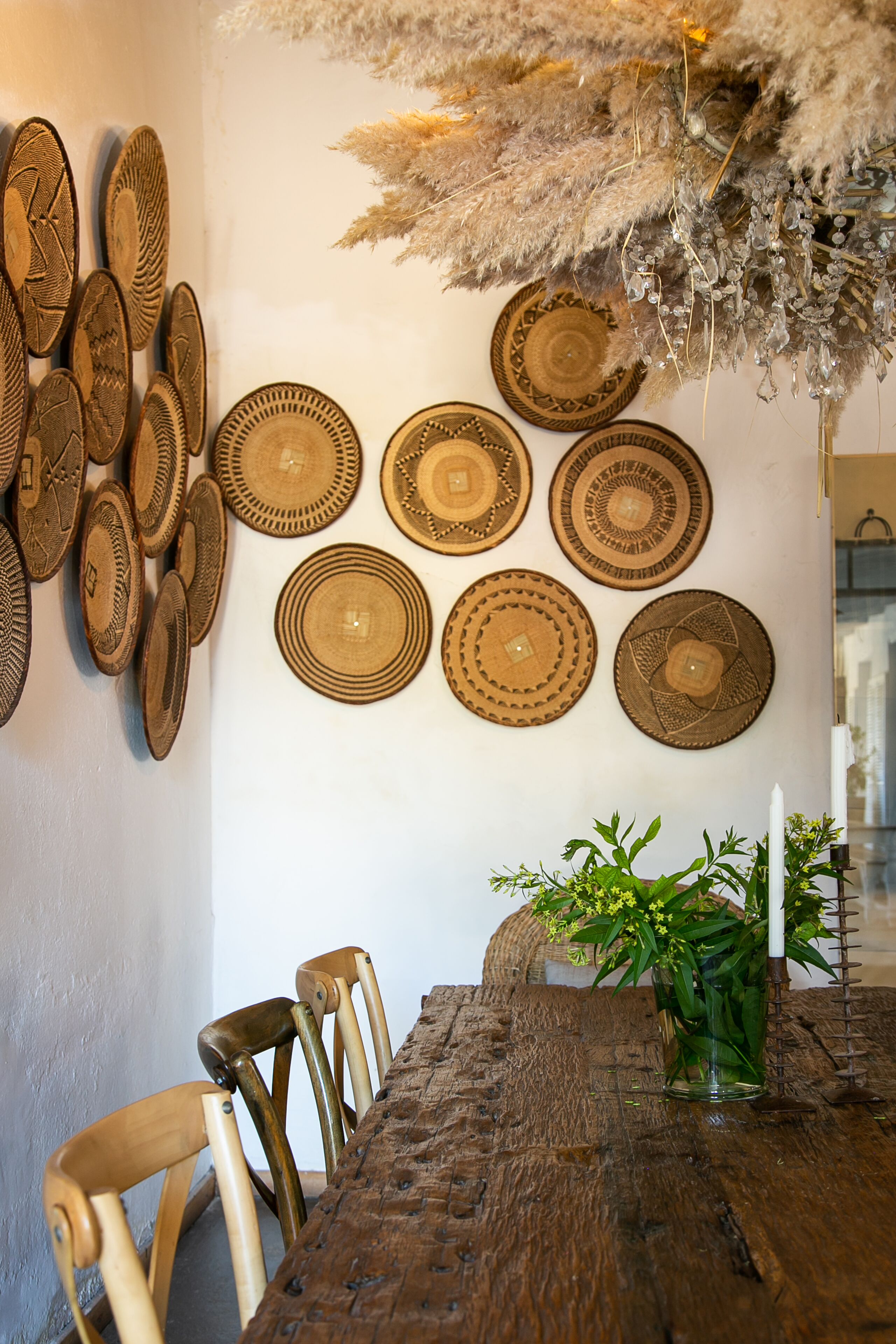 Un coin repas avec une table en bois, des chaises et des assiettes décoratives accrochées au mur.