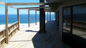 A wooden deck with a view of the ocean, supported by wooden beams and columns. - Wilderness Beach Resort (Wilderness)