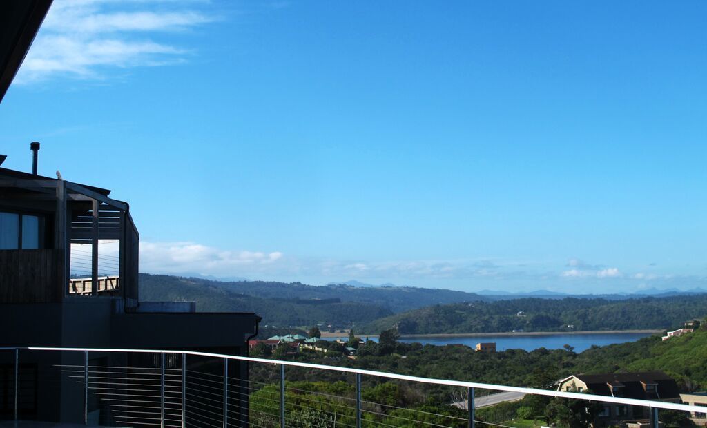 Ein modernes Gebäude mit einem Balkon mit Blick auf einen See und entfernte Berge.