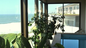 A room with large windows overlooking a beach and a building. - Wilderness Beach Resort (Wilderness)