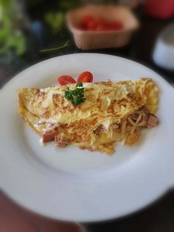 A plate with an omelette, garnished with a parsley leaf and cherry tomatoes.