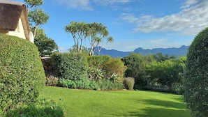 A well-maintained garden with neatly trimmed hedges, a variety of shrubs, and a clear view of distant mountains. - Paradise Cove Country House (Wilderness)