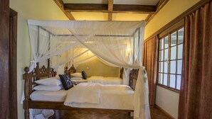 Una habitación con dos camas de madera, techo de madera y una ventana con cortinas.