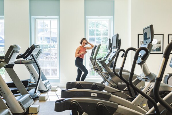 A gym with multiple treadmills, a person using a treadmill, and large windows with a view of greenery outside. - Colonial Houses, an Official Colonial Williamsburg Hotel (Williamsburg)