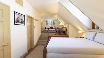 A hotel room with a large bed, a desk with a chair, a staircase, and a framed picture on the wall.