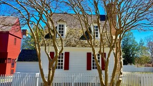 Una casa blanca con contraventanas rojas y valla de piquete blanca.