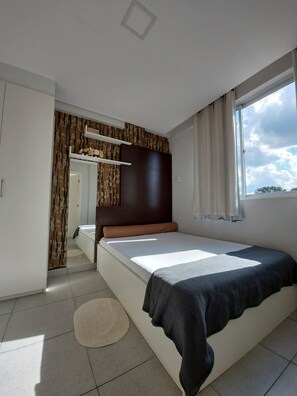 A bedroom with a bed, a window, a mirror, and a wardrobe. - Villa Tata Suites (Curitiba)