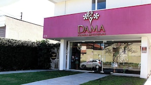 A building with a pink facade and the name "DAMA" prominently displayed. - Villa Tata Suites (Curitiba)